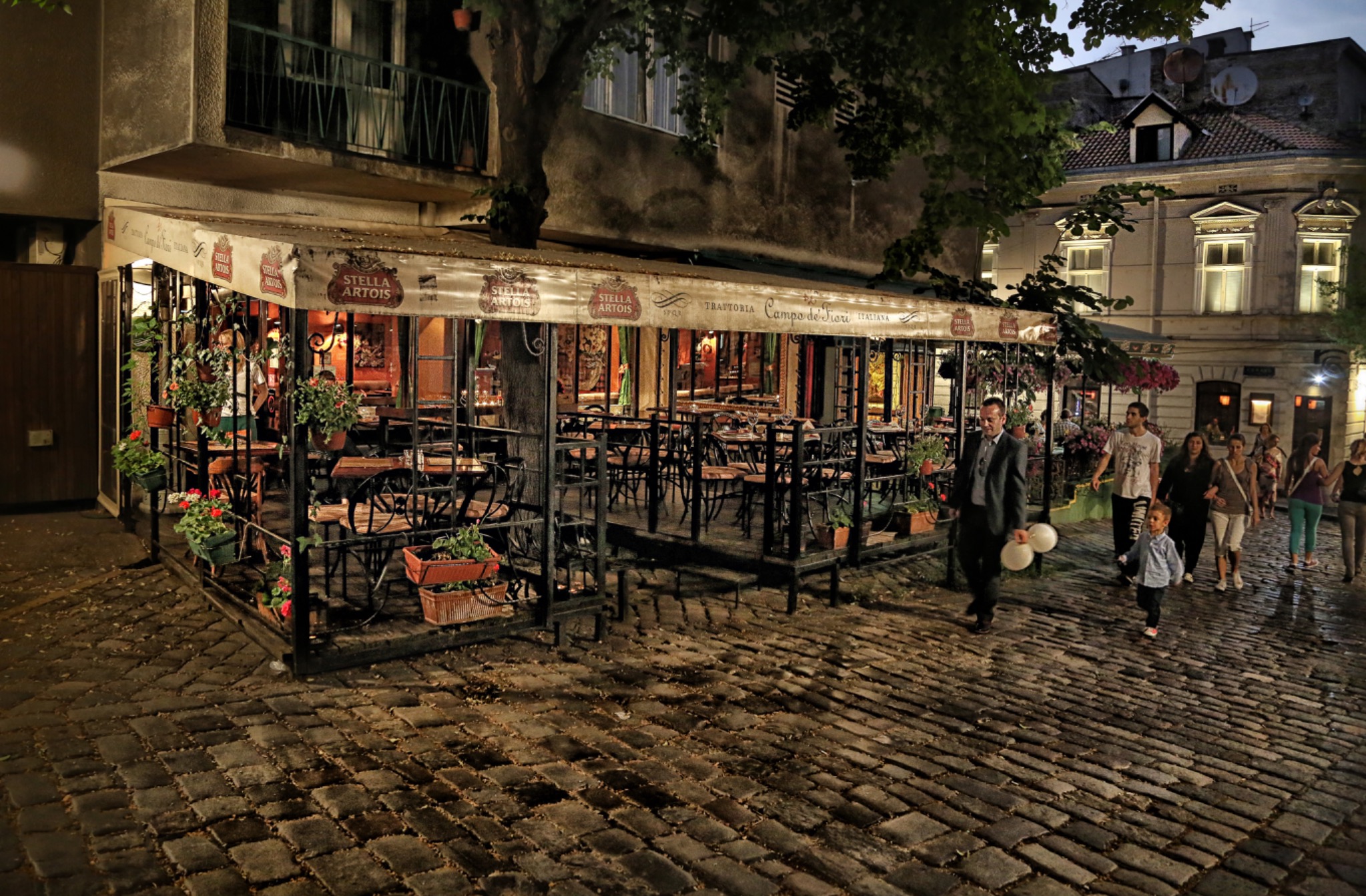 Skadarlija på kvällen med upplysta restauranger, gäster och den historiska kullerstensgatan.