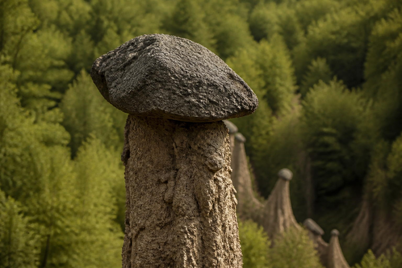 Redaktionell illustration: Close-up of a single towering earth pillar capped with a heavy volcanic andesite stone block