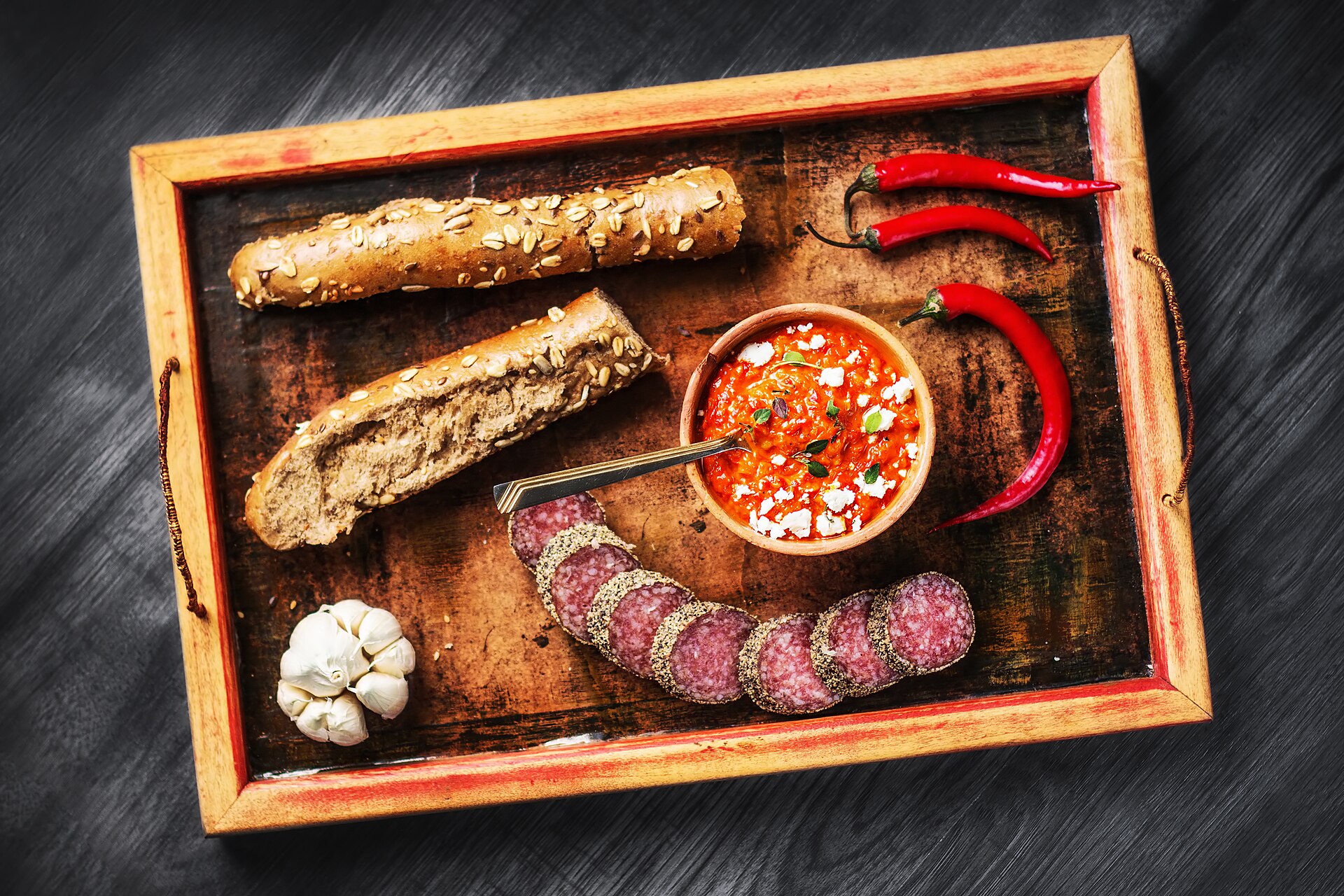 Traditionellt serverad ajvar med bröd på ett dukat bord.