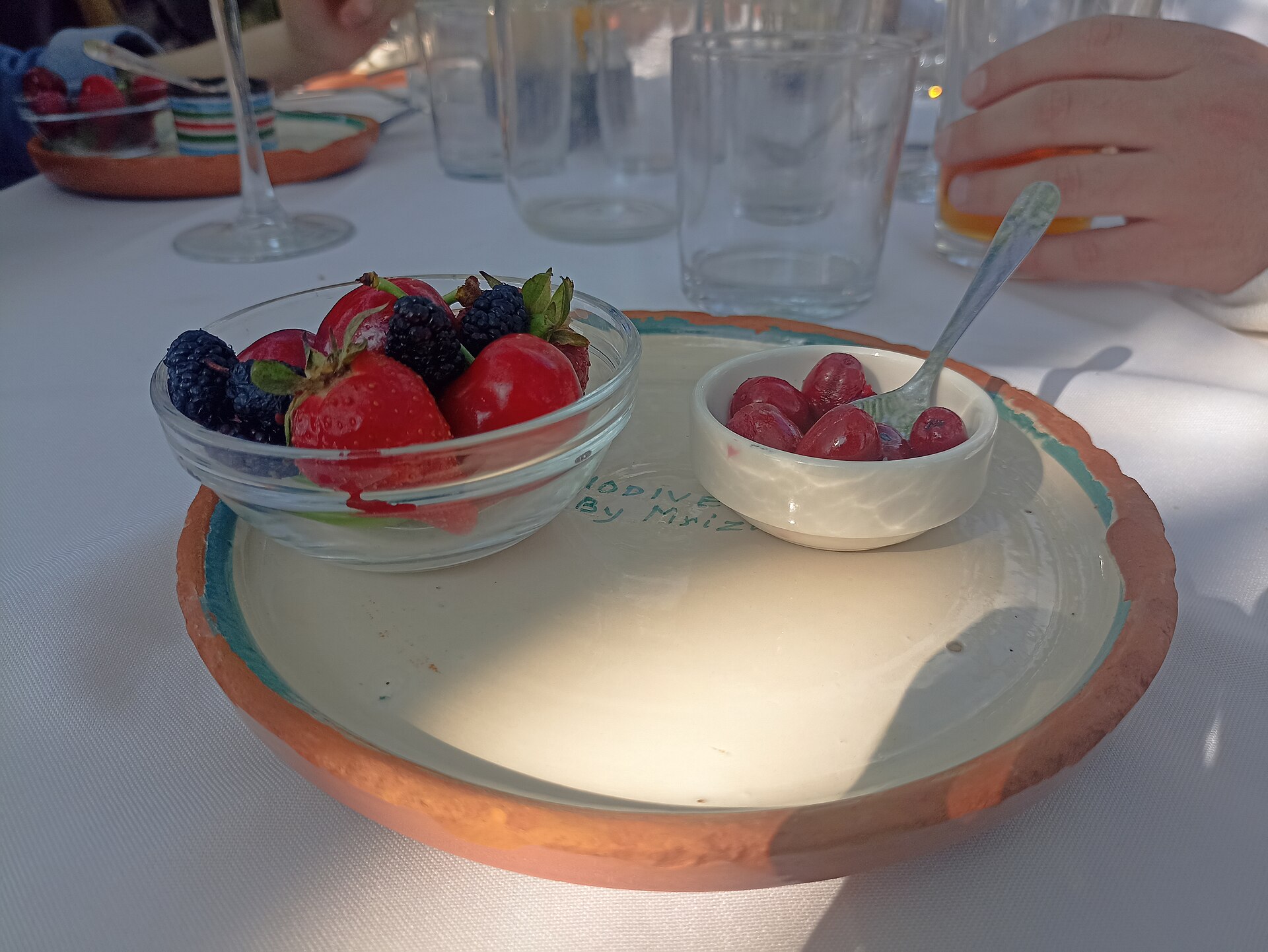 Färska bär serverade i glasskålar på en handgjord keramiktallrik med texten Mrizi.
