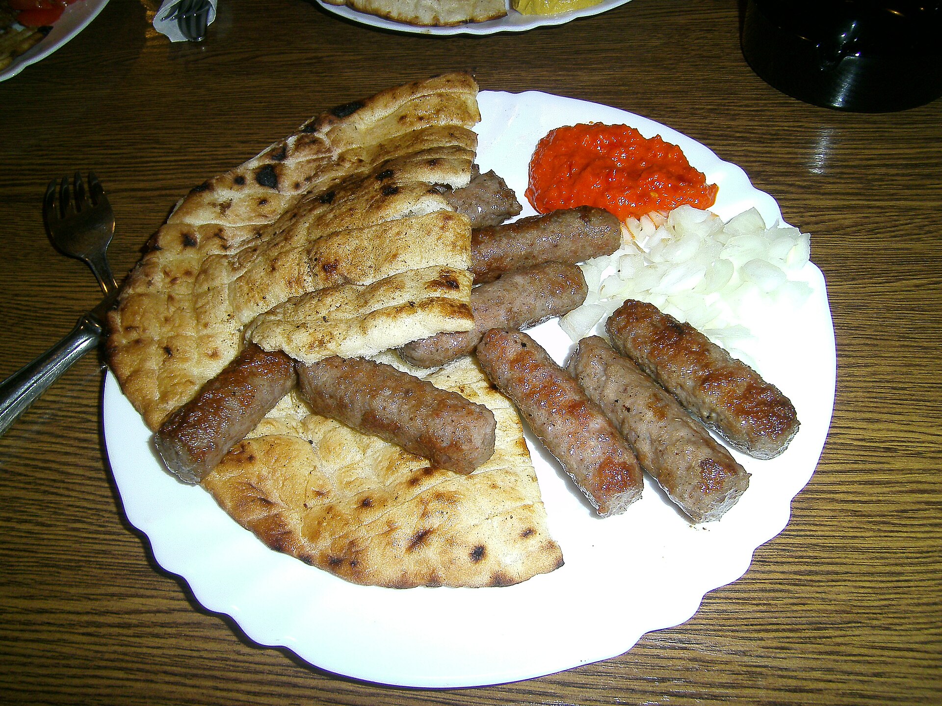 Nygrillade ćevapi serverade med bröd och lök.