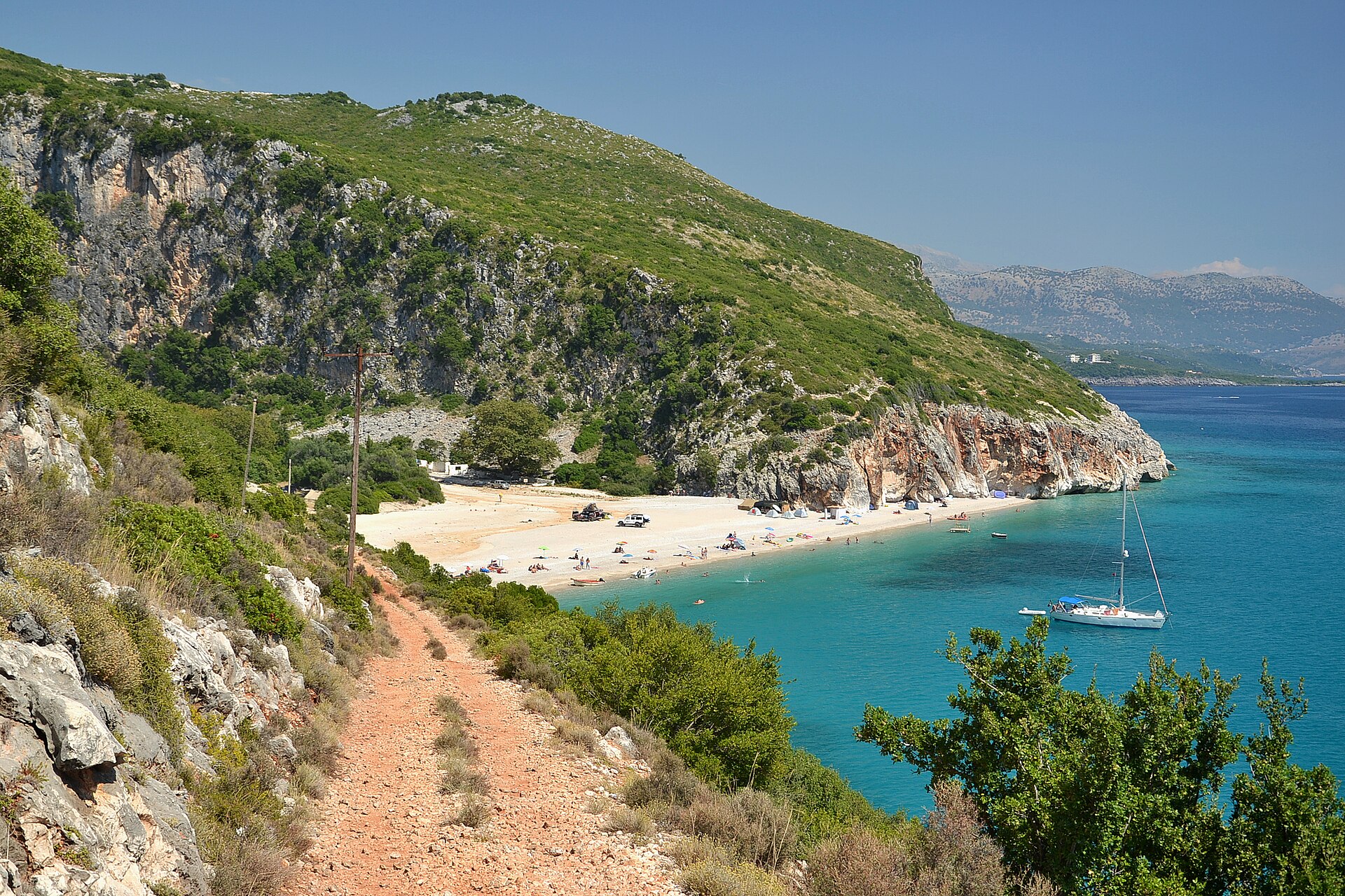 Vy över den natursköna Gjipe-stranden i Albanien med turkost vatten omgivet av höga, dramatiska klippor längs kusten.
