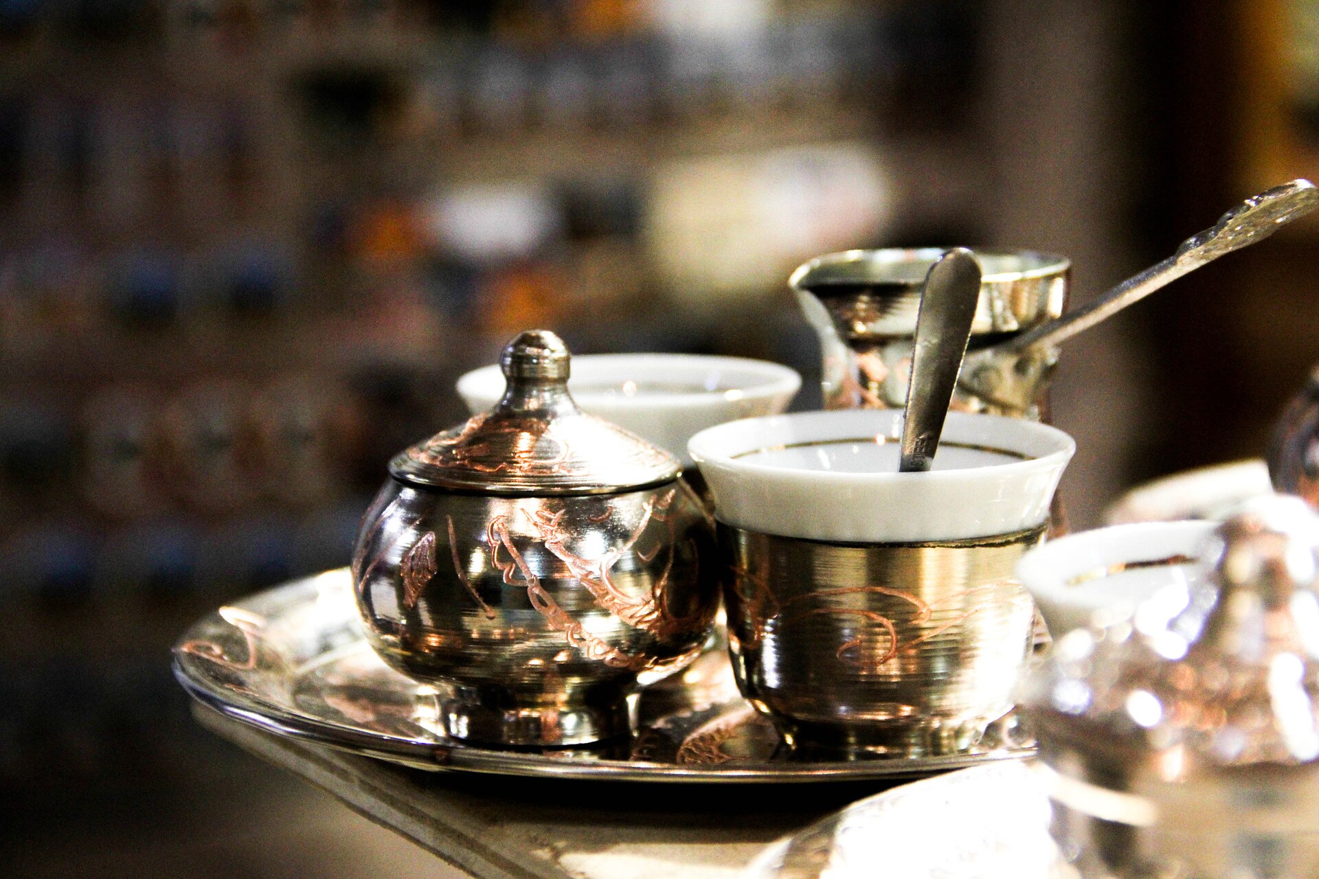 En traditionell bosnisk kaffekanna, džezva, i koppar tillsammans med en liten kaffekopp på en dekorerad metallbricka.