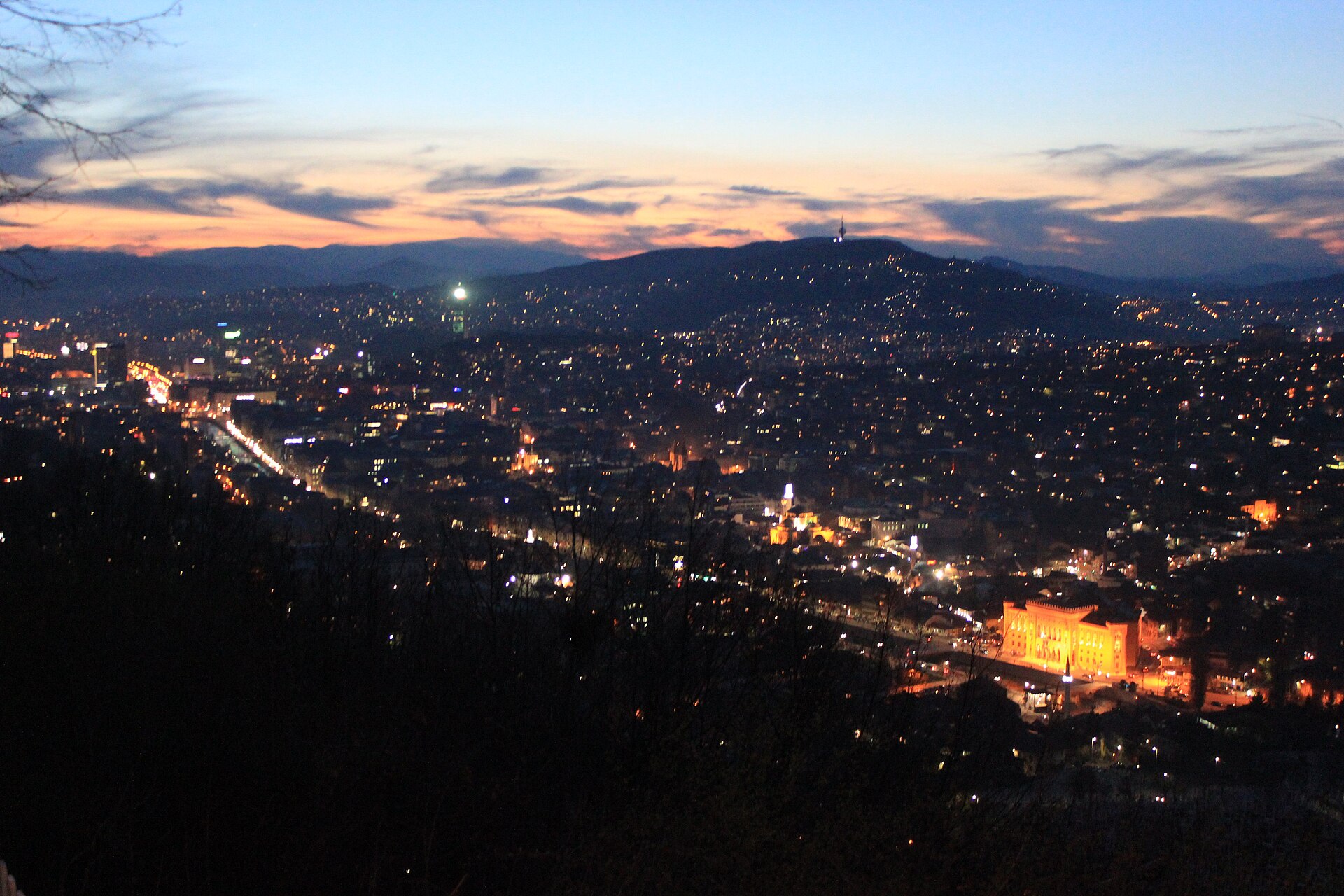 Stämningsfull panoramavy över Sarajevo med dess röda takåsar och omgivande kullar, som speglar stadens själ och melankoli.