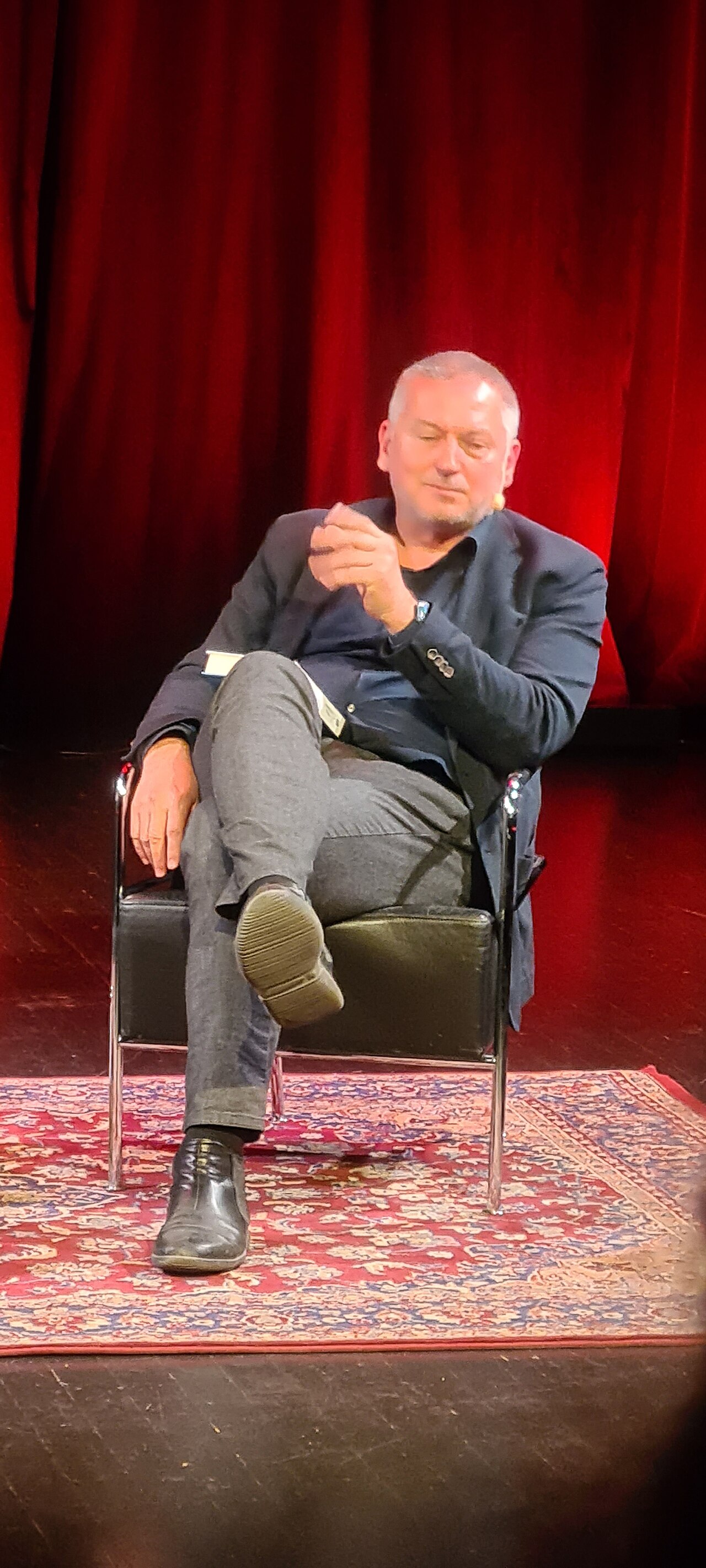 Den bulgariske författaren Georgi Gospodinov sitter på en scen framför en röd ridå under ett framträdande på Kulturhuset.