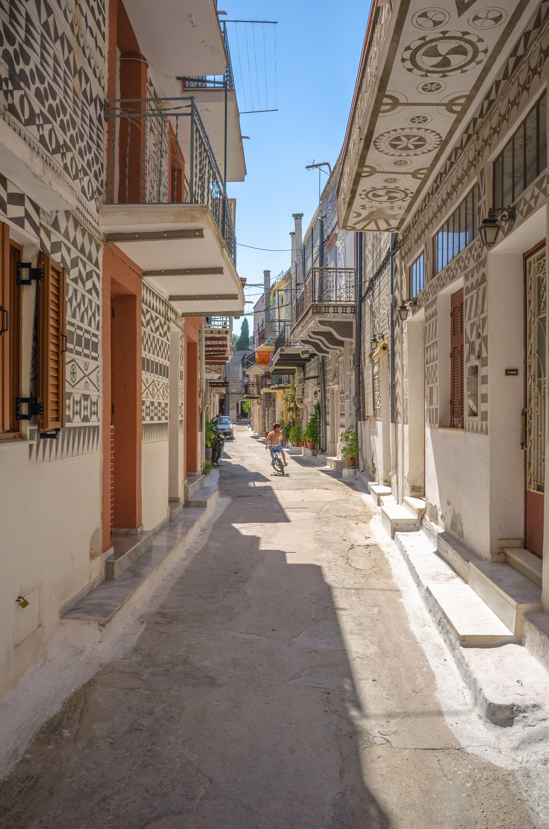 En smal gränd i den grekiska byn Pyrgi på ön Chios, där husfasaderna är prydda med traditionella svartvita geometriska mönster.