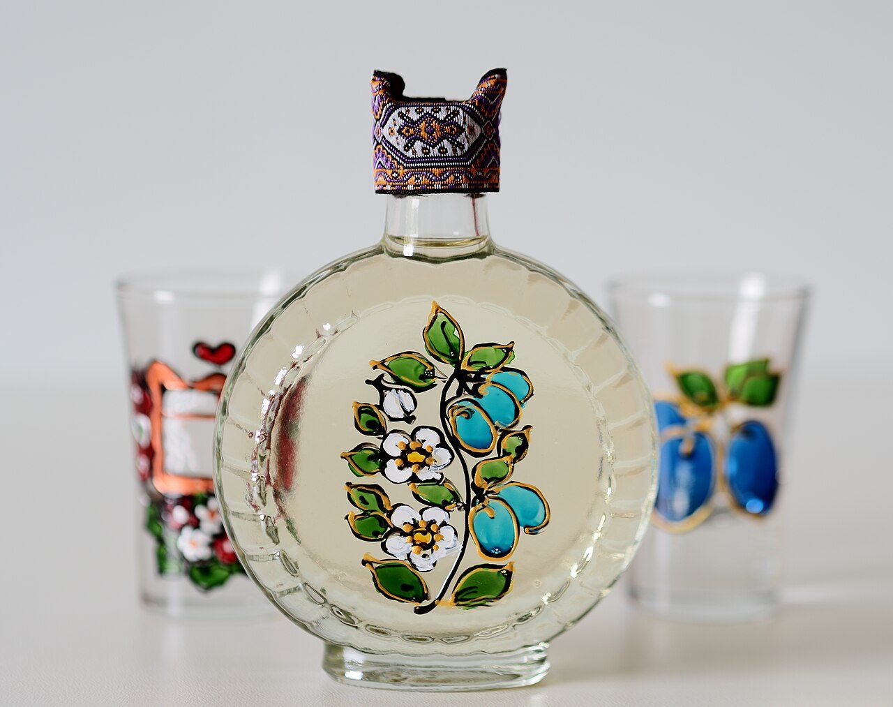 En dekorerad čutura-flaska med šljivovica tillsammans med två målade snapsglas.