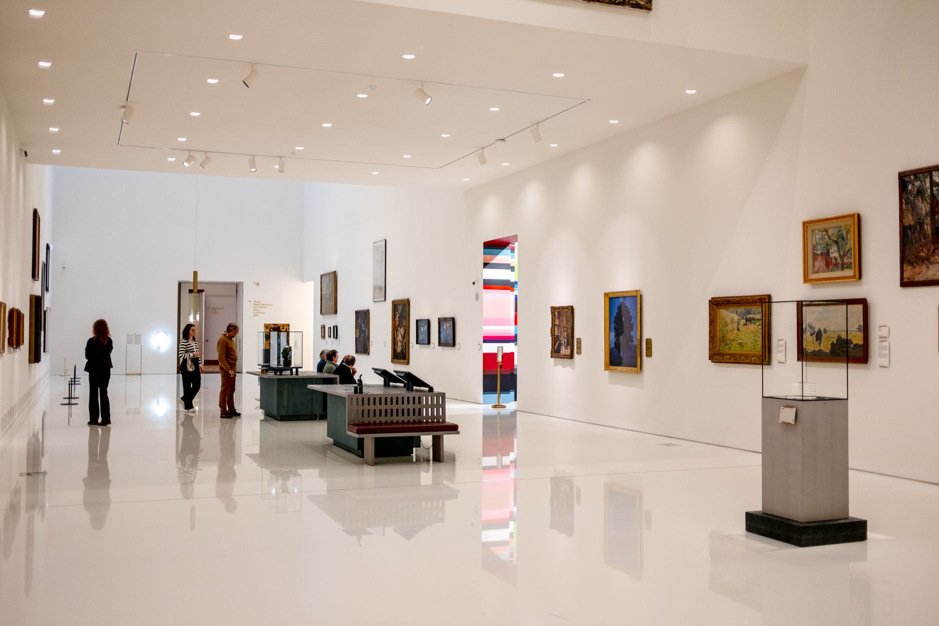 Besökare i en ljus, modern museisal som studerar konstverk och utställningsföremål.