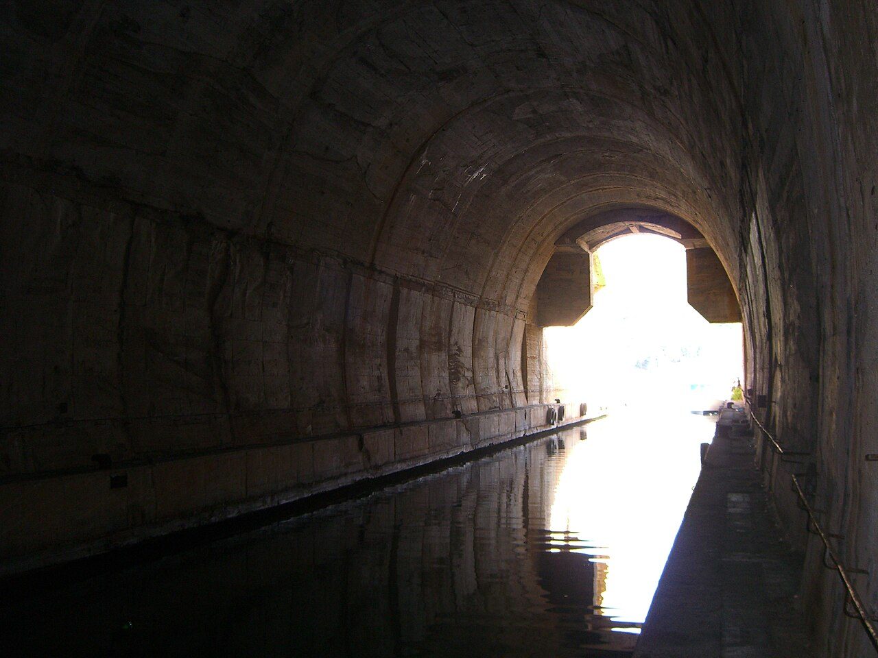 Militär tunnel på ön Vis med vattenkanal och dagsljus vid tunnelmynningen.