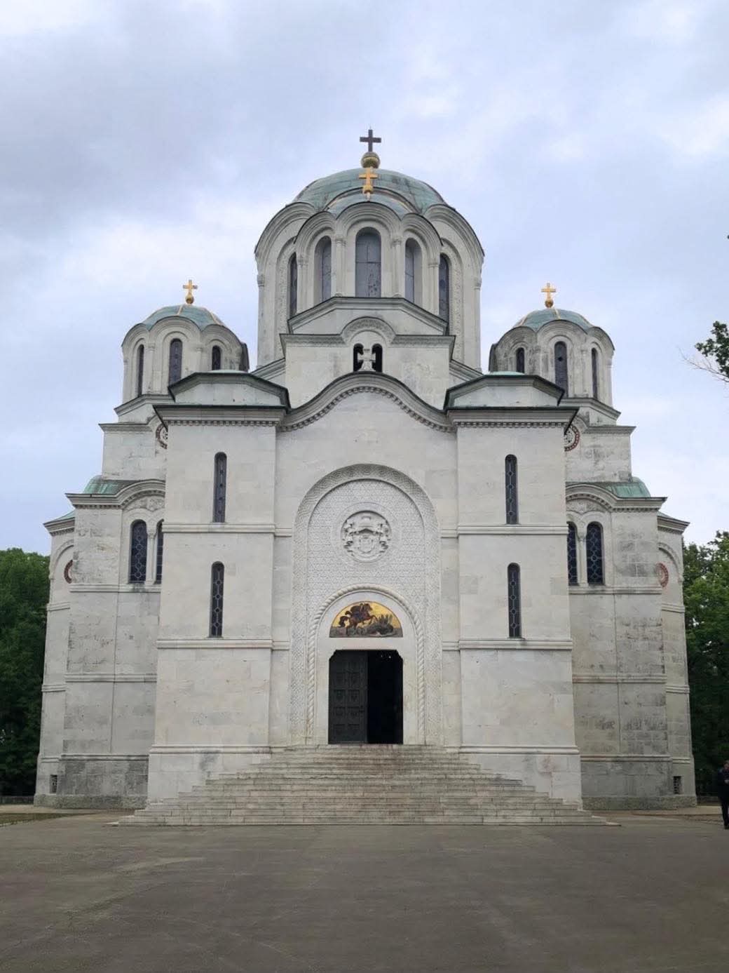 Sankt Georgs kyrka på Oplenac i vit marmor med fem kupoler, sedd från trappan framför huvudentrén.